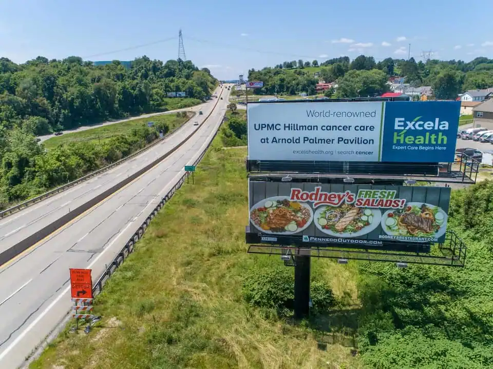 A double stacked Penneco Outdoor Advertising billboard with 2 faces towers above Route 30 in North Huntingdon, PA