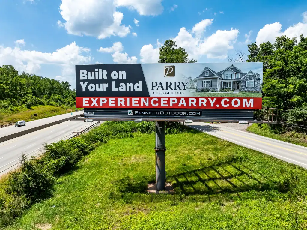 a Penneco Outdoor Advertising billboard featuring a Western Pennsylvania builder stands alongside a highway